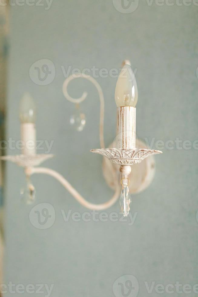 A beautiful view of the old, classic and retro style wall lamp, sconces with crystal on a grey light wall. Beautiful view and background photo