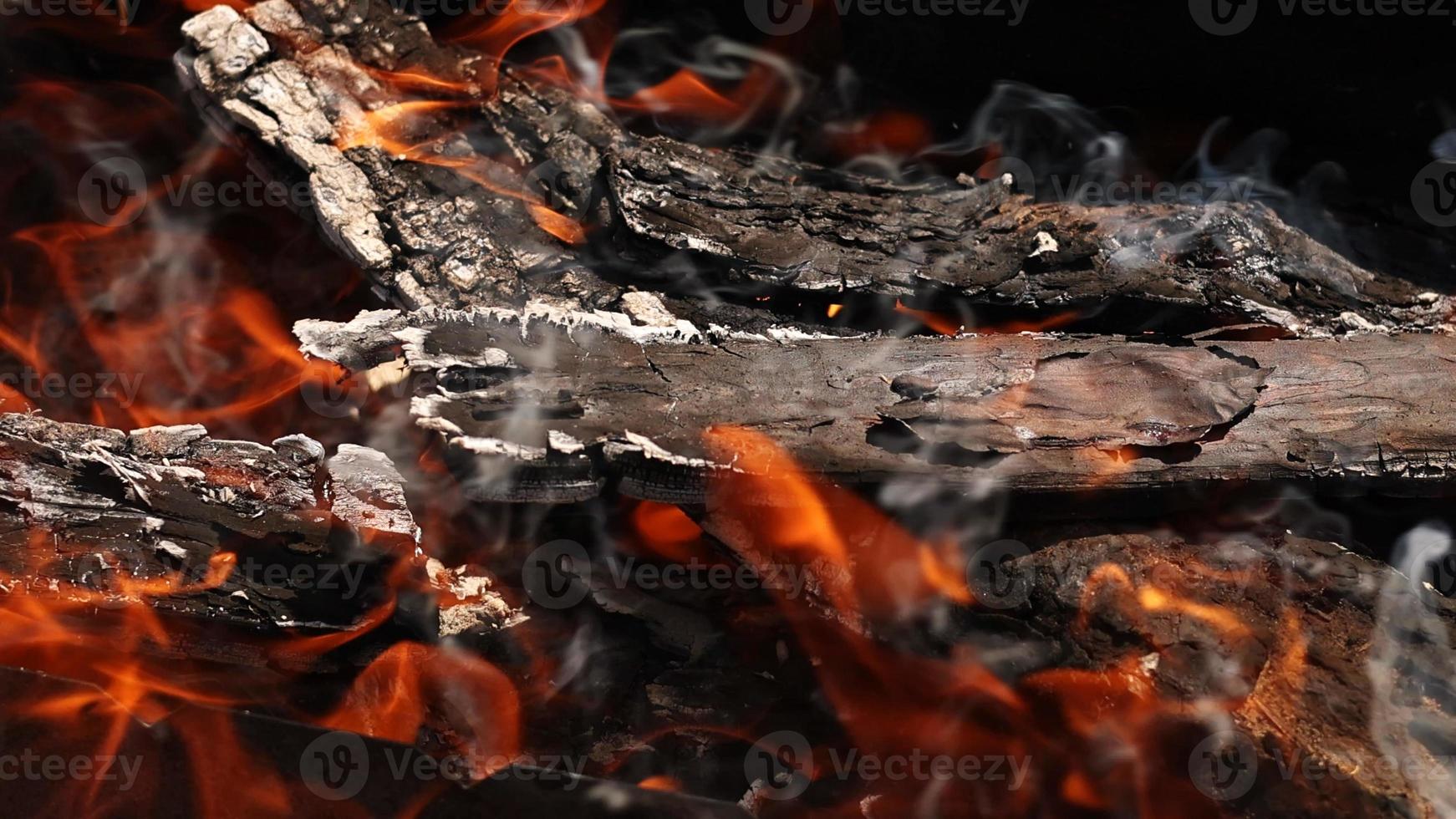 burning firewood up close. barbecue woods, flame fire, ash coals burning outdoors. smoke going up from burning wood logs, campfire orange flames. photo