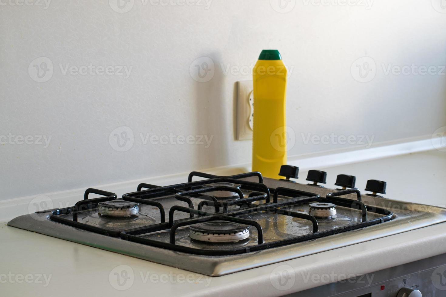 The cleaning of the kitchen. Very dirty gas stove. Cleaning the gas stove with a cleaning agent. photo