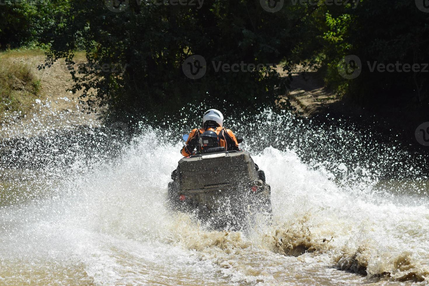 The man on the ATV crosses a stream photo