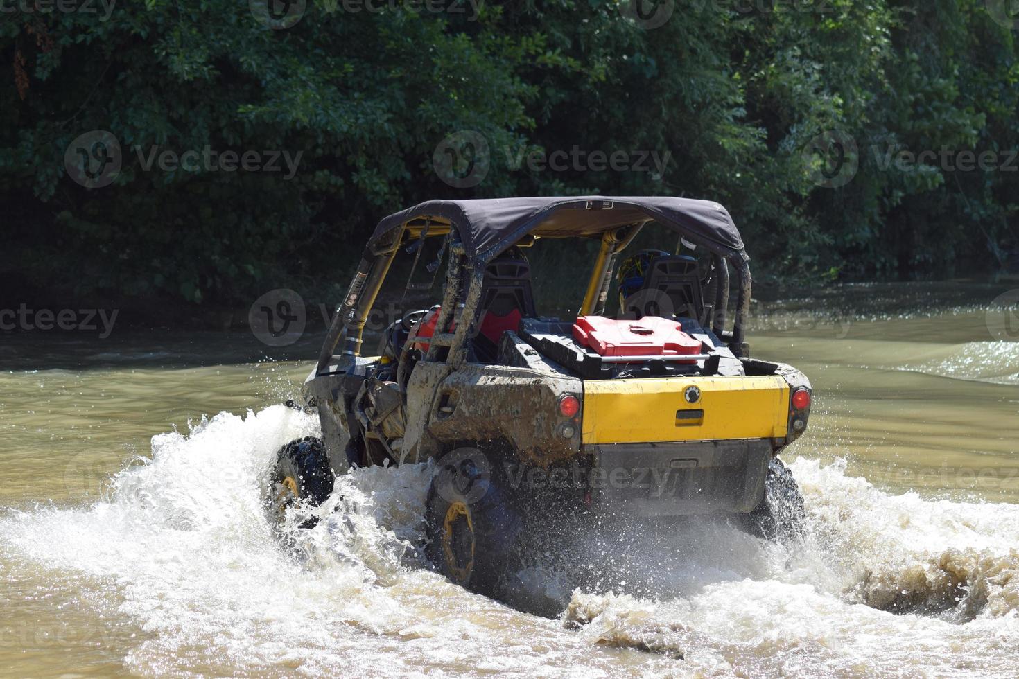 The man on the ATV crosses a stream photo