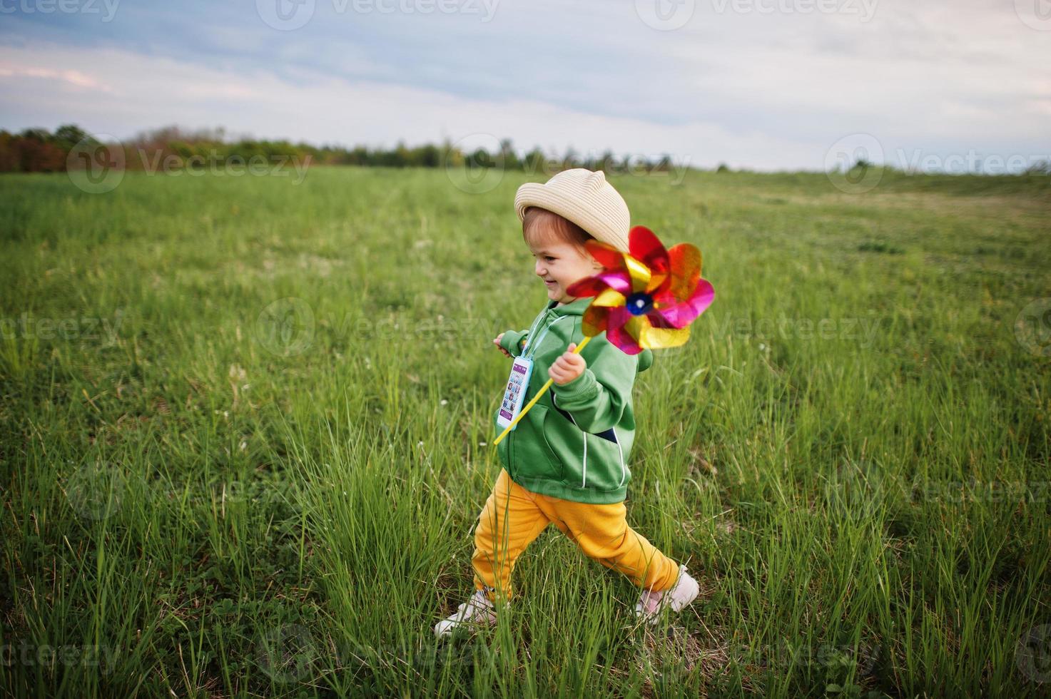 Babay girl with pinwheel at meadow. photo