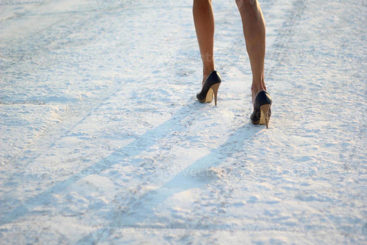 cropped photo of female legs in shoes on snow. selective focus