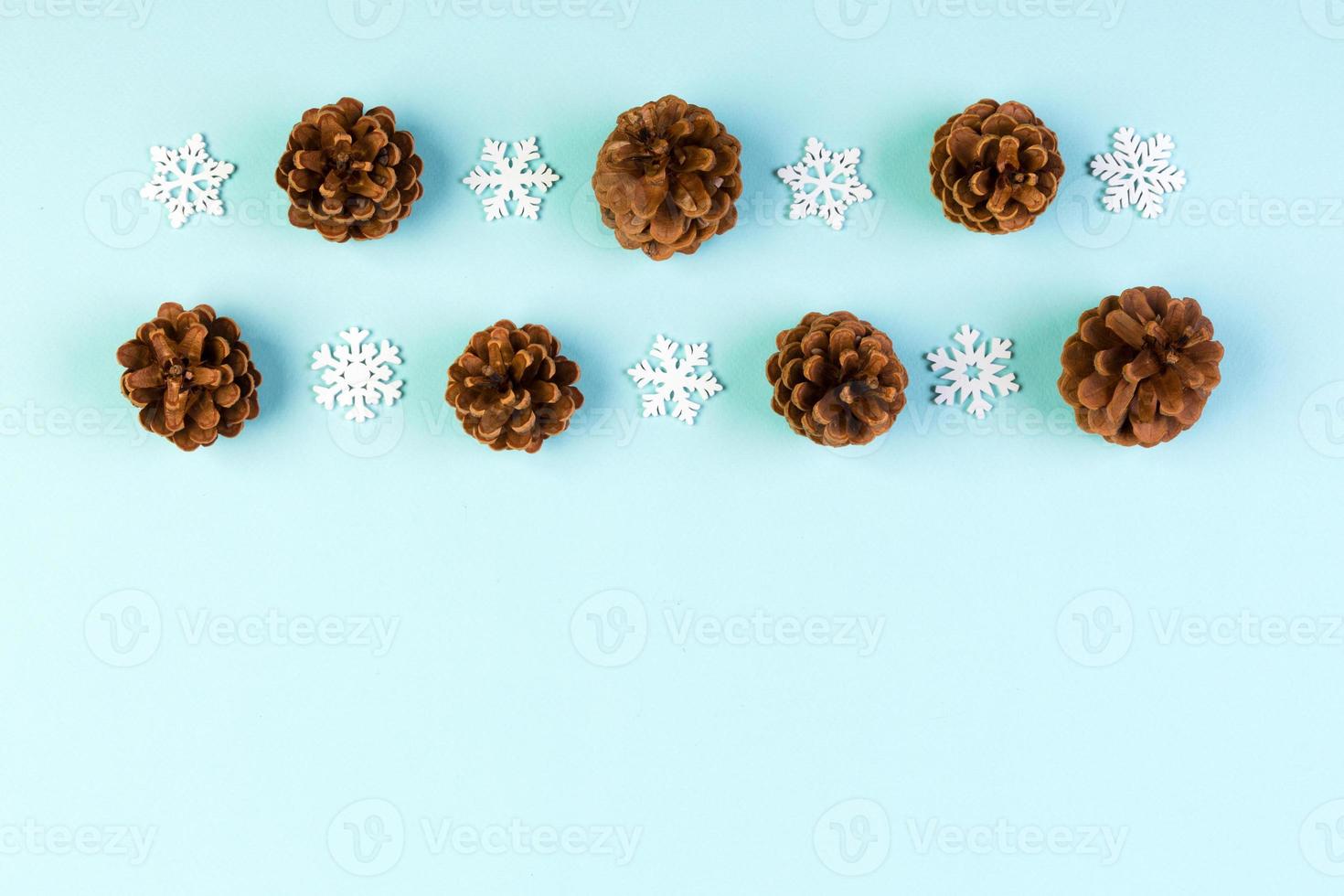 Top view of New Year ornament made of white snowflakes and pine cones on colorful background. Winter holiday concept with empty space for your design photo