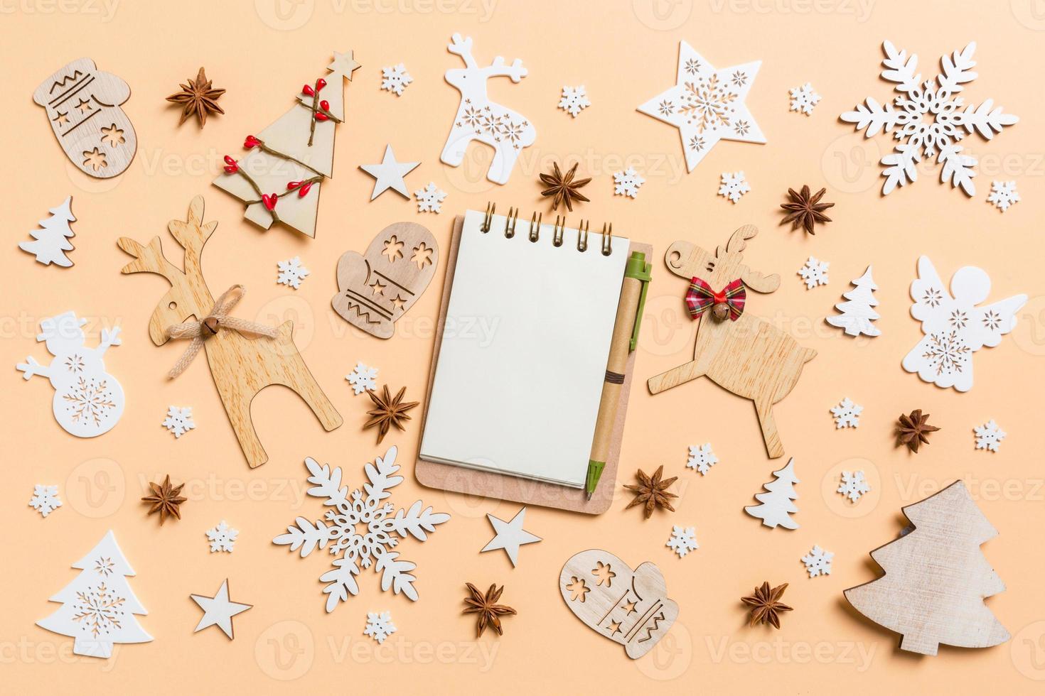 Festive decorations and toys on orange background. Top view of notebook. Merry Christmas concept photo