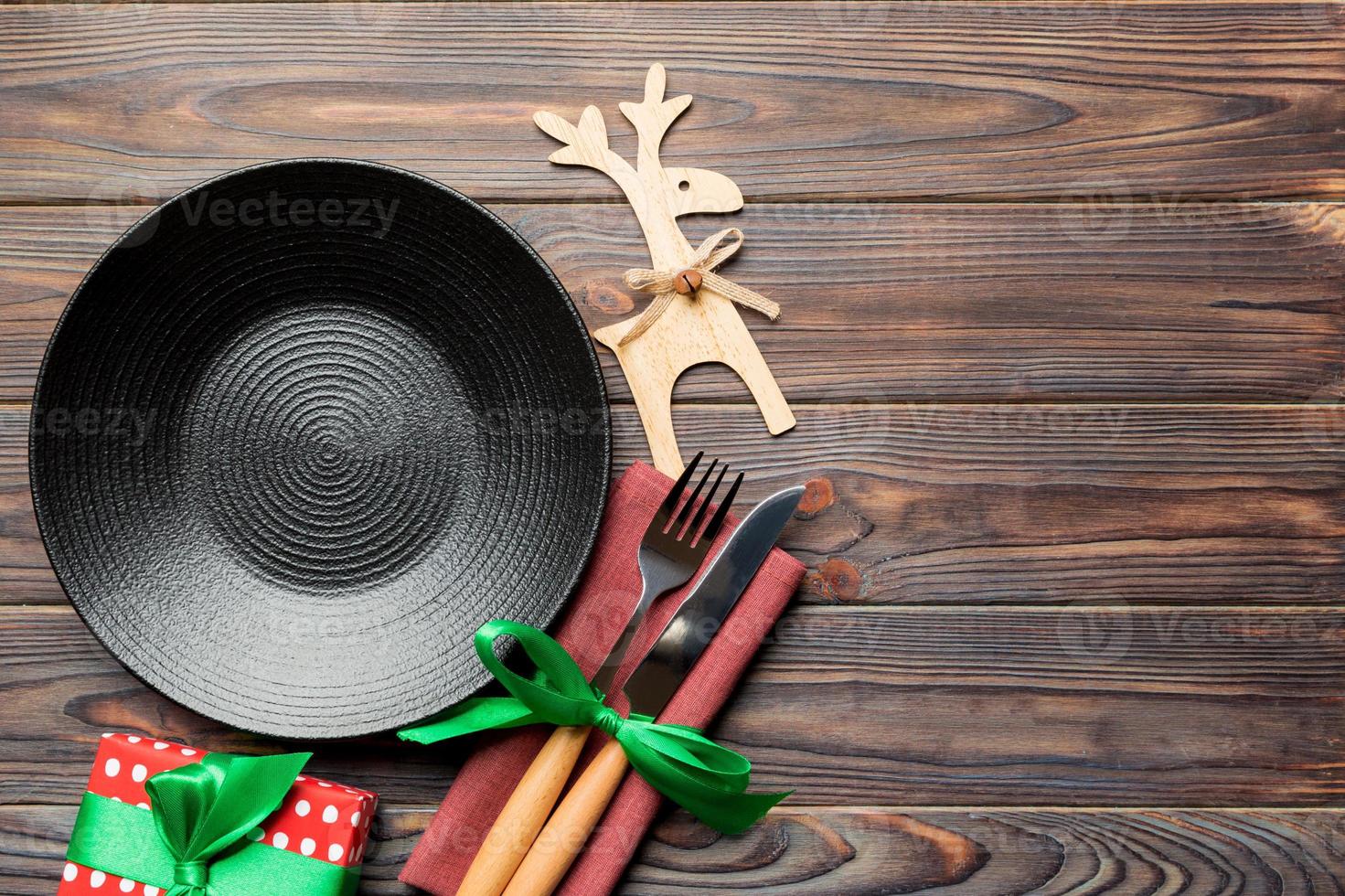 Top view of plate, fork and knife served on Christmas decorated wooden background. New Year Eve concept with copy space photo