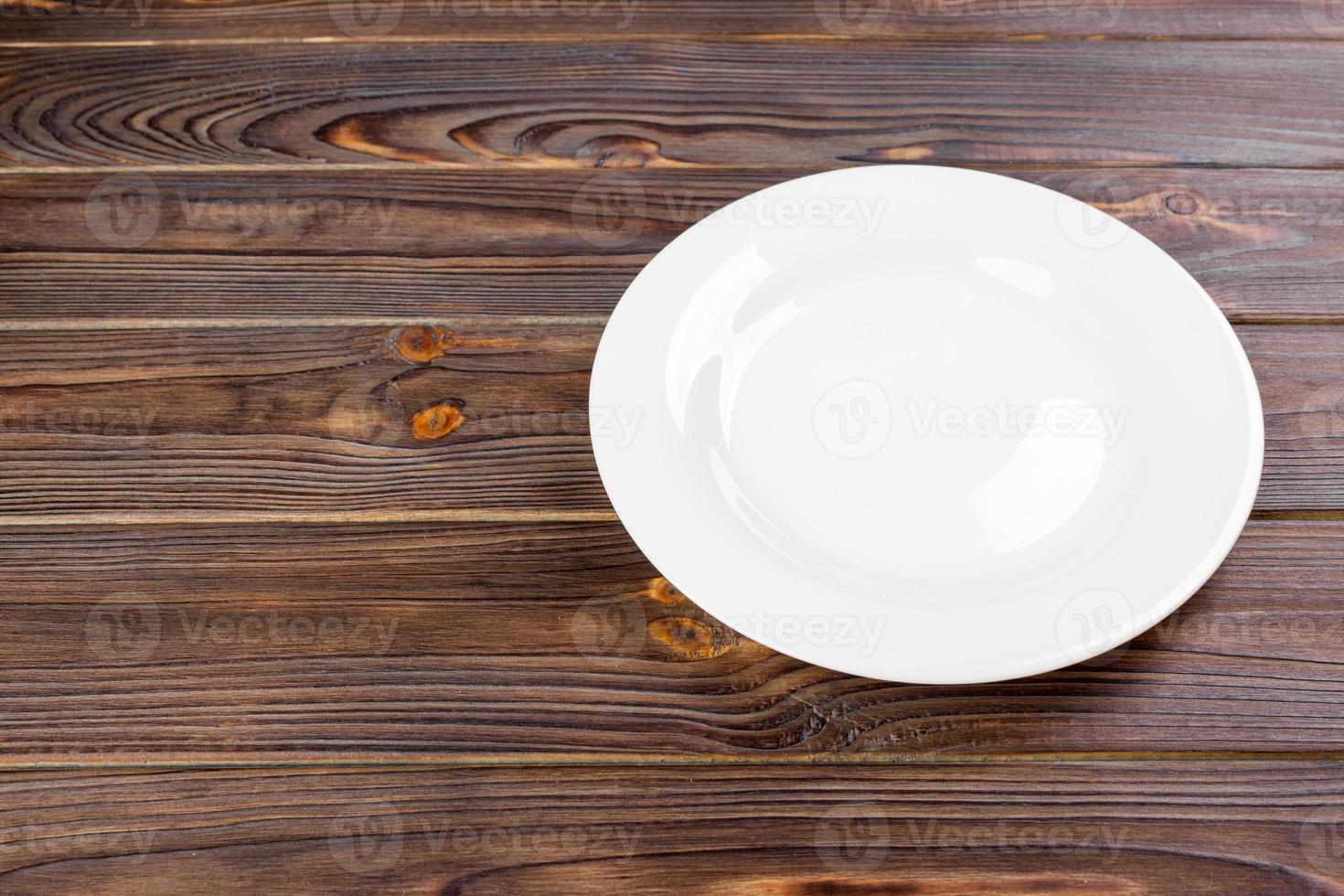 Empty white plate on wooden table top view. photo
