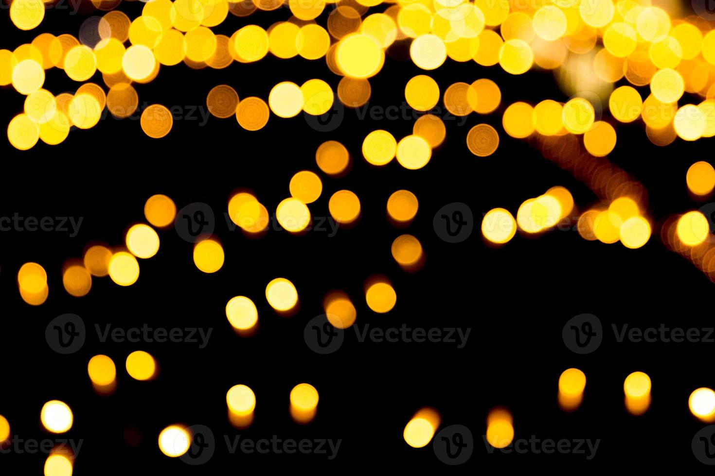 Gold abstract bokeh background. defocused and blurred many round yellow light on dark background photo