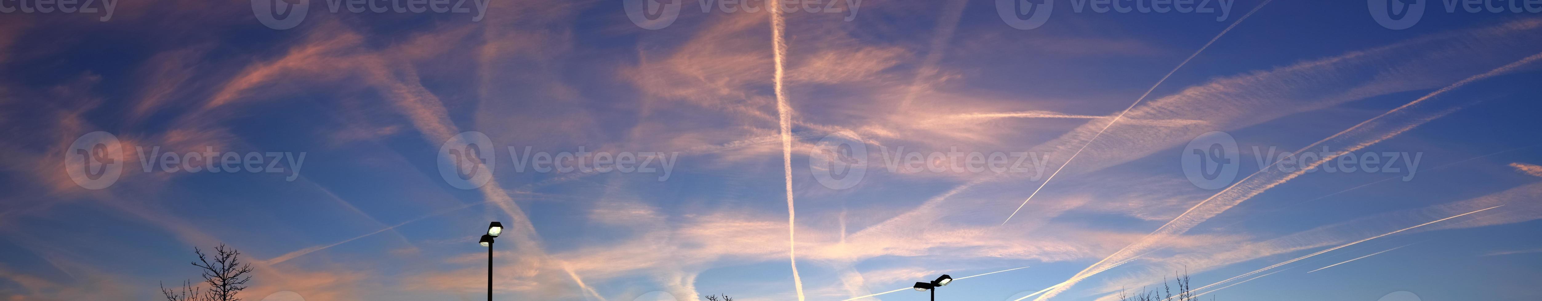 Estelas de condensación de aviones en el cielo azul entre algunas nubes foto