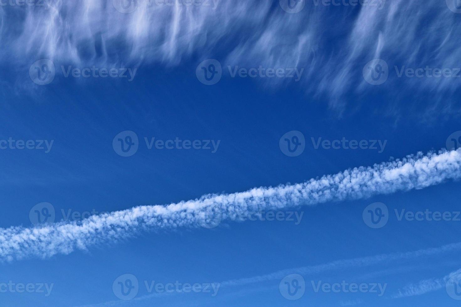 Estelas de condensación de aviones en el cielo azul entre algunas nubes foto