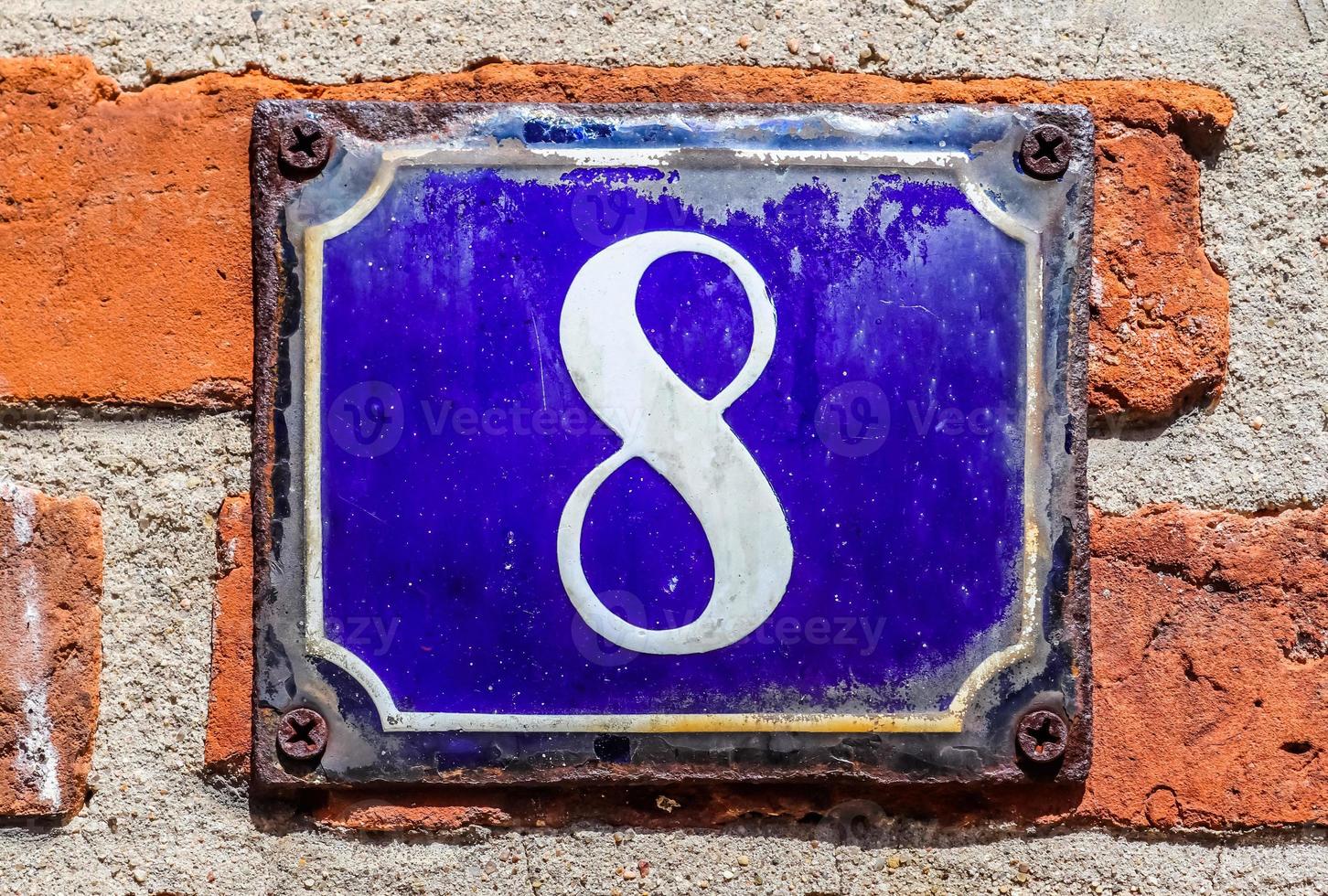 Old brick wall. Texture of old weathered brick wall with a number 8 on a blue sign. photo