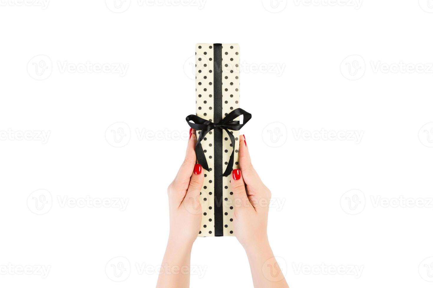 Woman hands give wrapped Christmas or other holiday handmade present in yellow paper with black ribbon. Isolated on white background, top view. thanksgiving Gift box concept photo