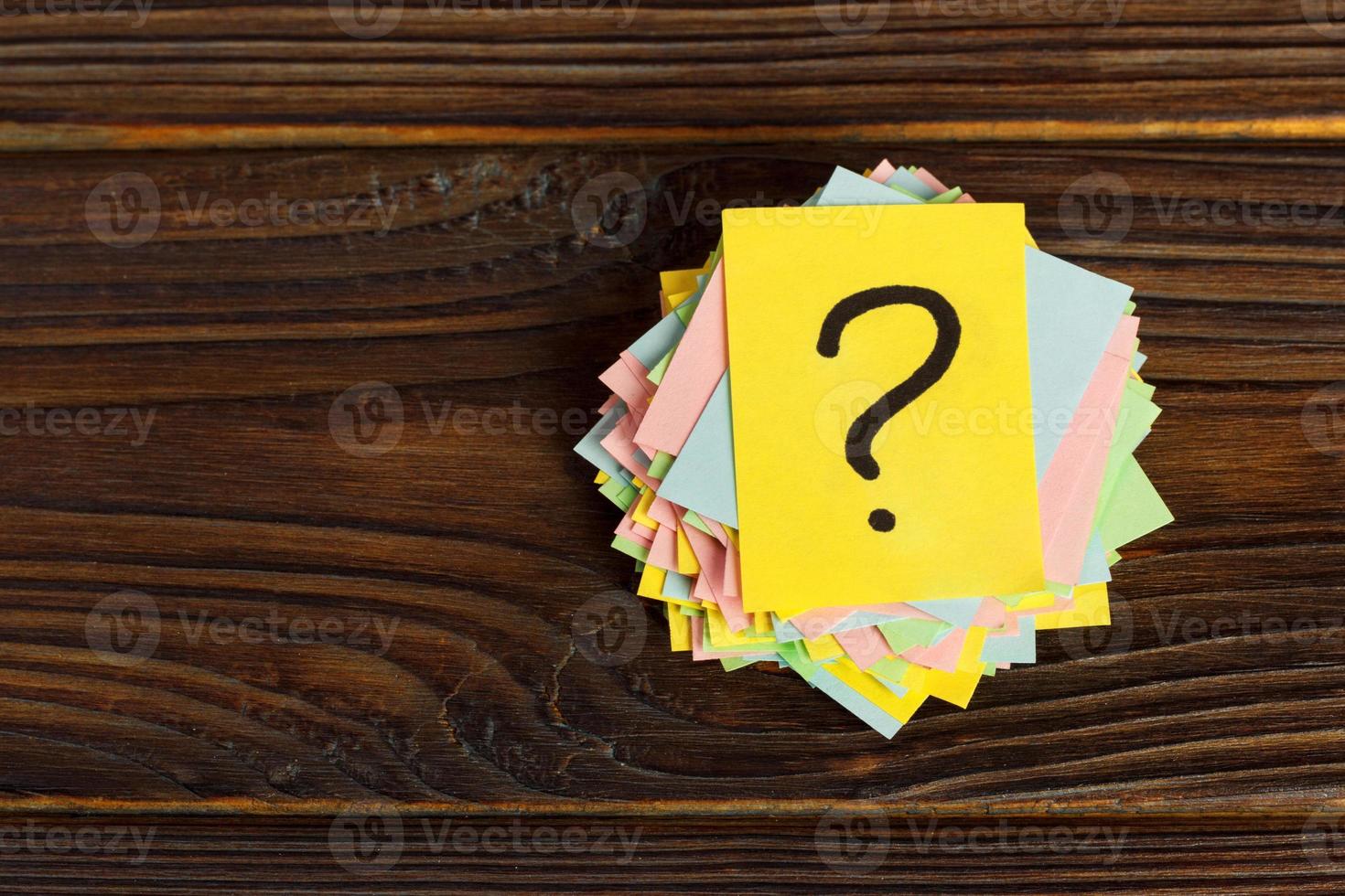 Question mark paper heap on wooden table concept for confusion photo