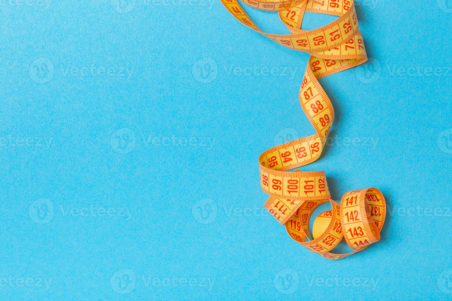 Tangled measuring tape with space for your idea. Sewing and tailor concept on blue background photo