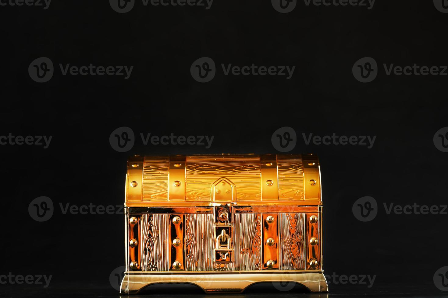 Gold treasure chest on a black textured background. photo