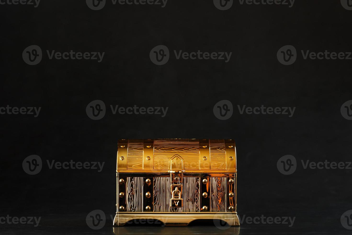 Gold treasure chest on a black textured background. photo