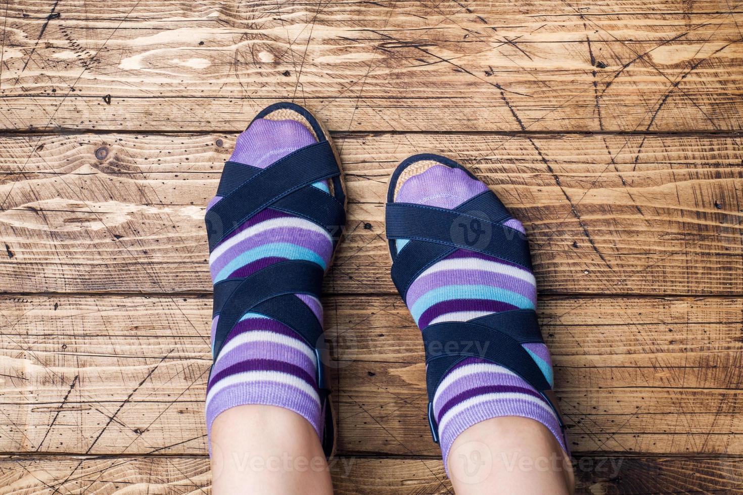 Women's feet in socks and sandals on wooden background. photo