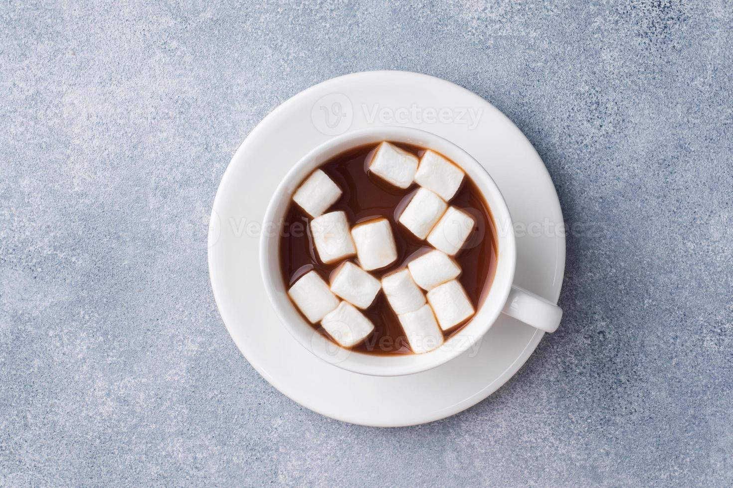 taza de chocolate caliente con malvavisco en el centro de la mesa gris foto