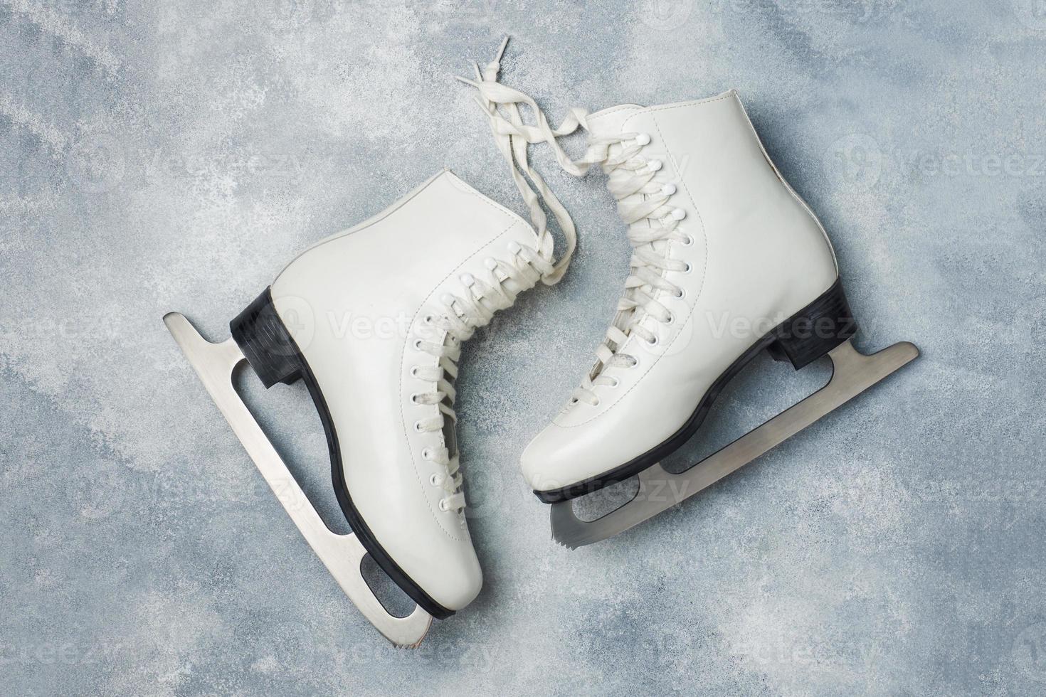 Concept winter holidays. White figure skates on grey background. photo