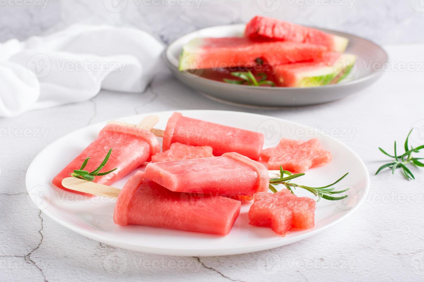Watermelon popsicle and pieces of watermelon on a plate on the table. Homemade dessert photo