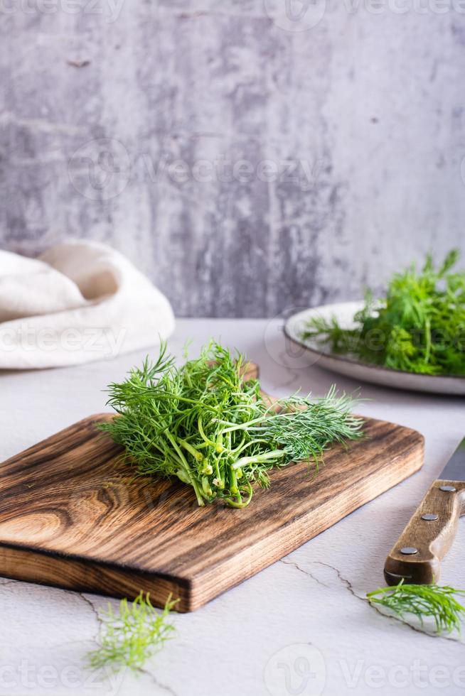 A bunch of fresh dill on a cutting board on the table. Organic seasoning. Vertical view photo