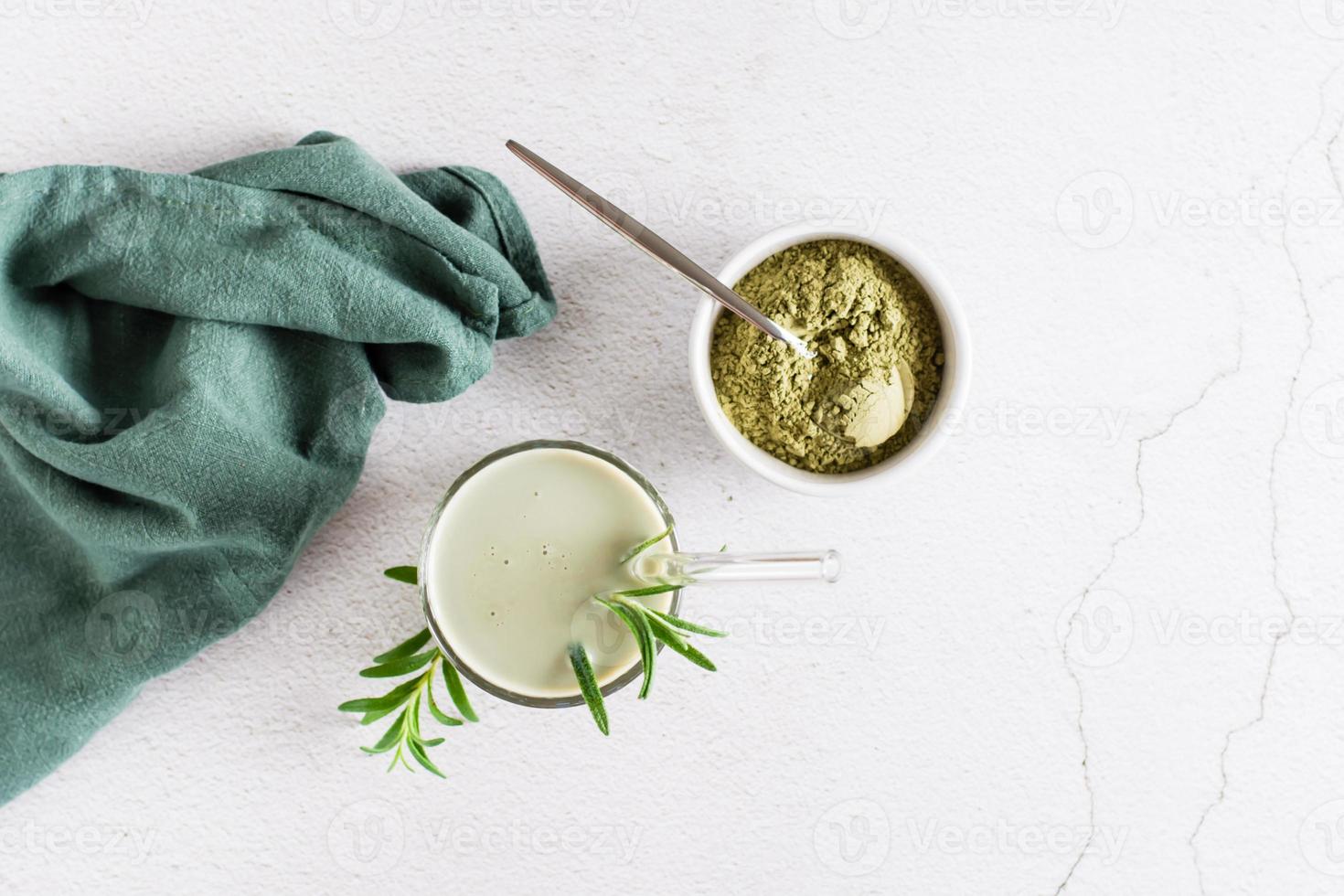 Matcha latte in a glass and powder in a bowl on the table. Homemade trendy drink. Top view photo