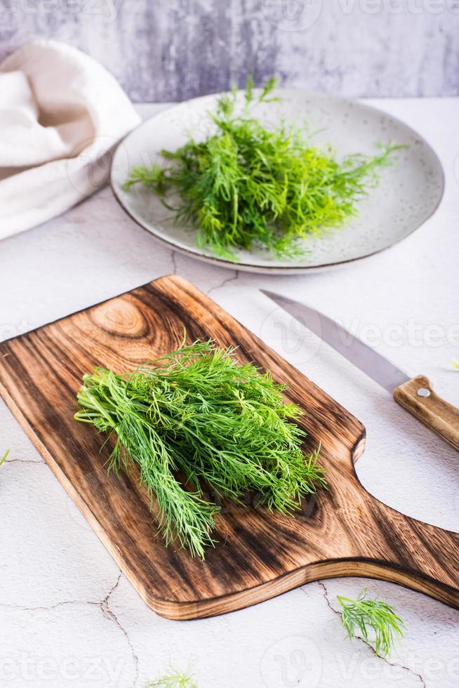 A bunch of dill on a cutting board on the table. Organic natural seasoning. Vertical view photo