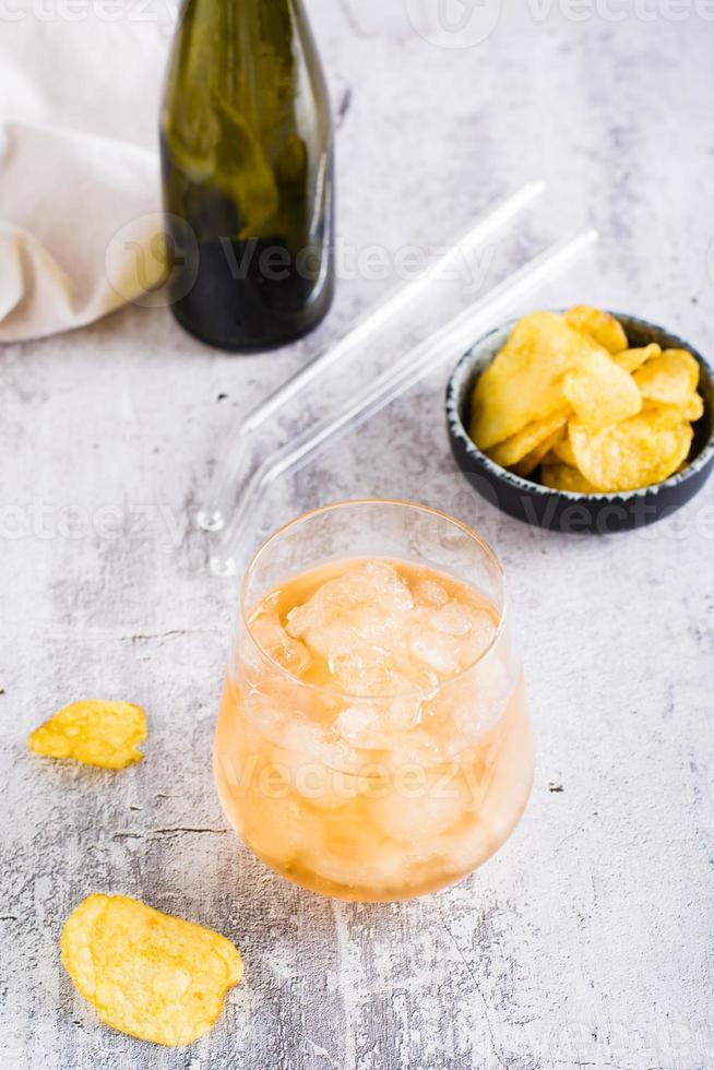 Beer slush in a glass and chips in a bowl on the table. Trendy summer drink. Vertical view photo