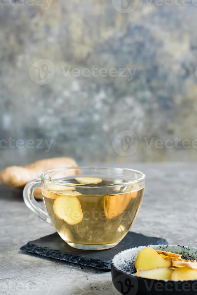 Fresh ginger tea in a cup and chopped ginger in a bowl on the table. Natural Vitamins. Vertical view photo