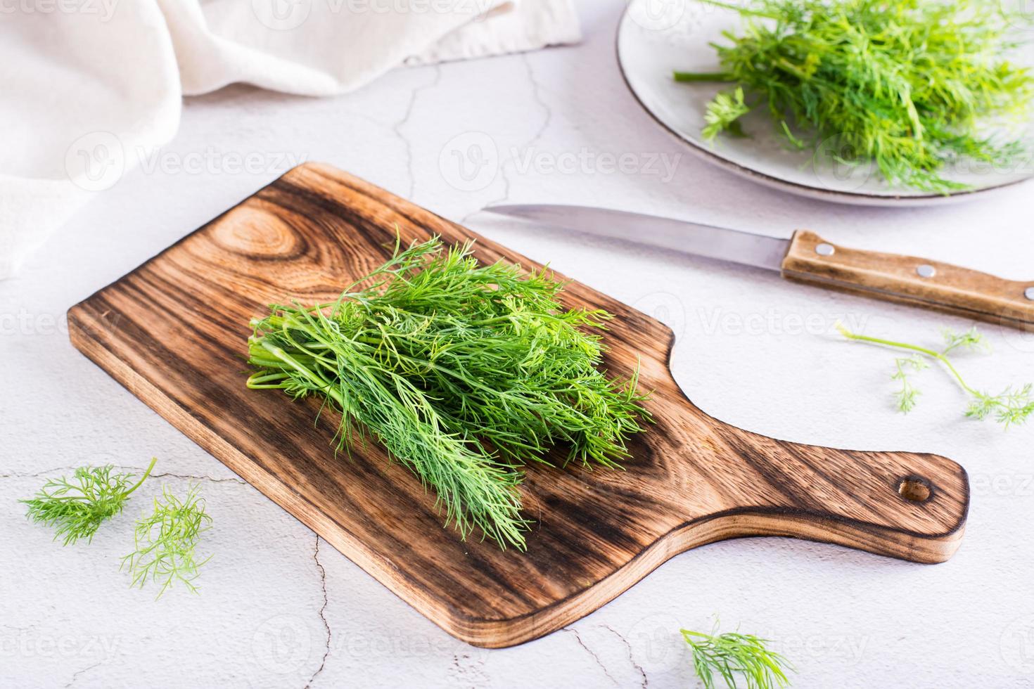 A bunch of dill on a cutting board on the table. Organic natural seasoning. photo