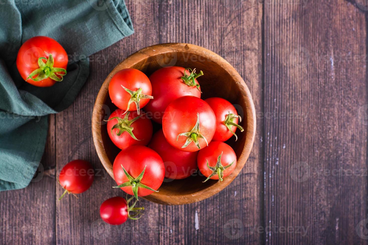 Organic ripe tomatoes in a bowl on a wooden table. Harvest and local products. Top view photo