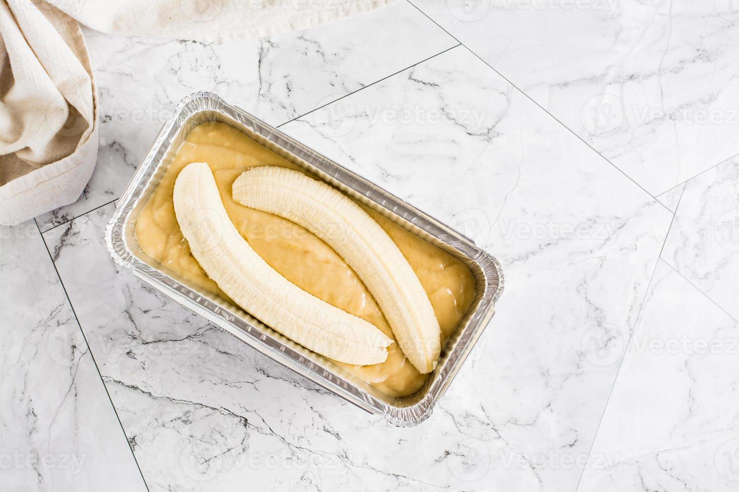 Raw dough for banana bread in a baking dish on the table. Social media trendy. Top view photo