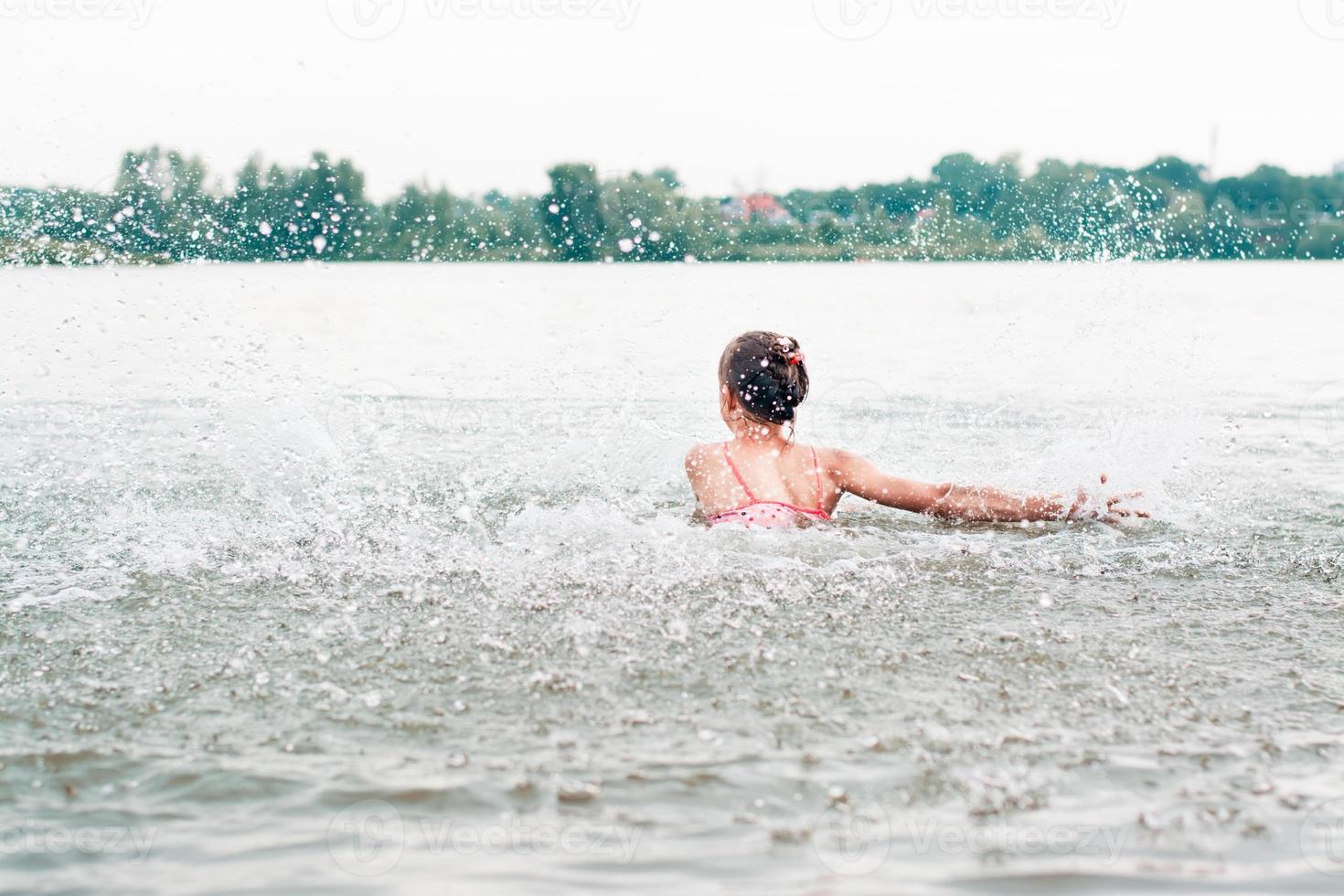 The girl stands with her back and splashes in the river. Local tourism. Summer vacation photo