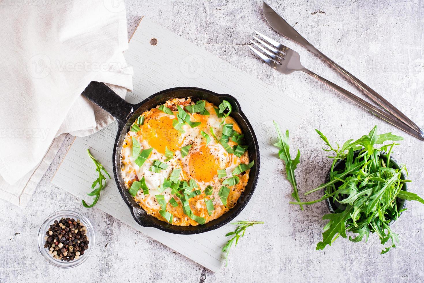 Shakshuka with tomatoes and arugula in a pan. Traditional mediterranean dish. Top view photo