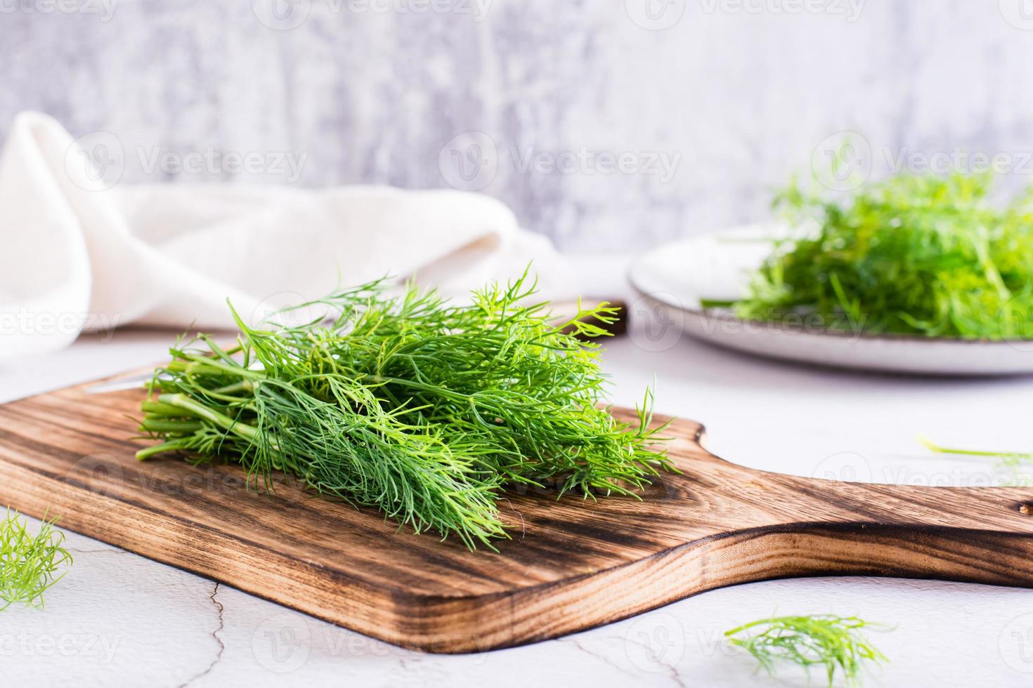 A bunch of fresh dill on a cutting board on the table. Organic seasoning. photo