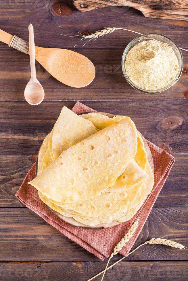 Homemade corn mexican tortillas wrap on a board on the table. Top and vertical view photo