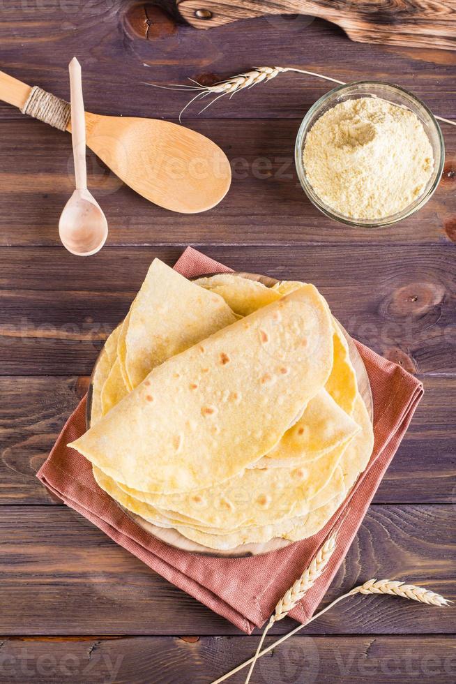 tortillas mexicanas de maíz caseras envueltas en un tablero sobre la mesa. vista superior y vertical foto