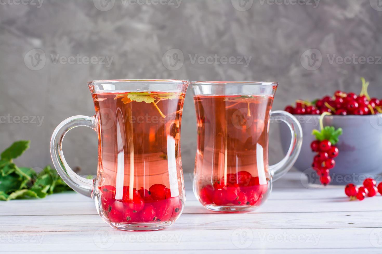 Red currant compote in cups on the table. Homemade summer drinks. photo