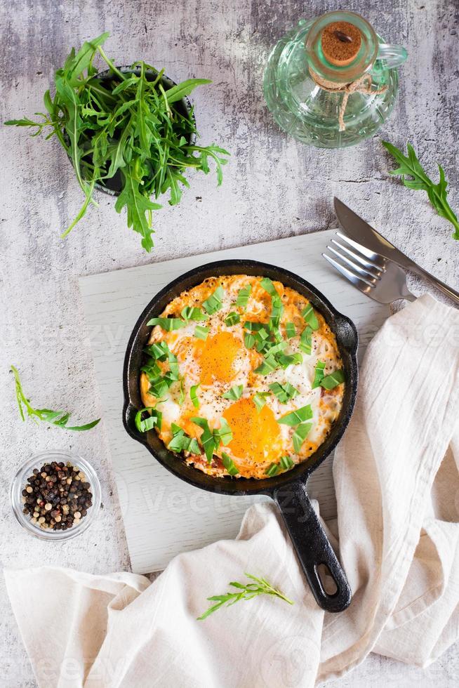 Shakshuka with poached eggs in spicy tomato pepper sauce in a frying pan. Top and vertical view photo