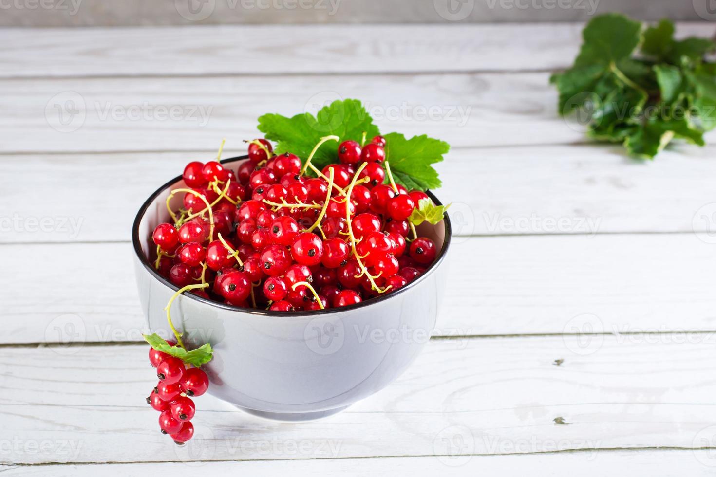 Fresh red currant berries in a bowl on the table. Summer organic food. photo
