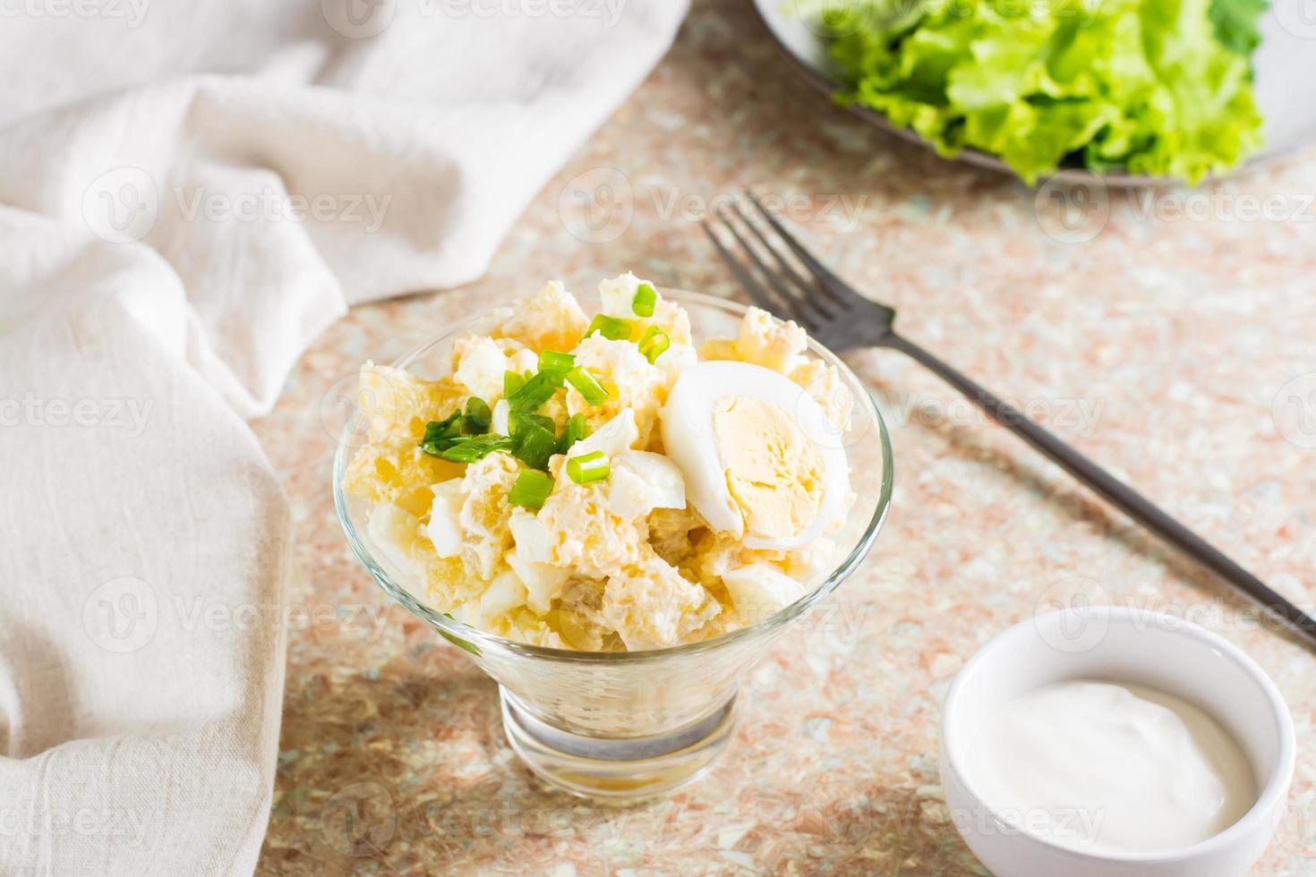 Potato salad with boiled egg, green onion and mayonnaise in a bowl on the table photo