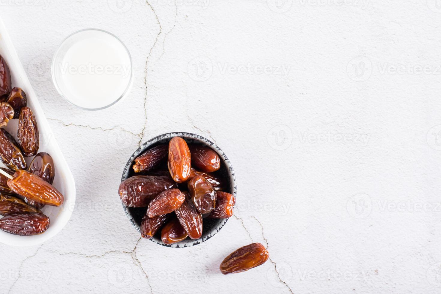 Dates in a bowl and a glass of milk on the table. Food for the holy month of Ramadan. Top view photo