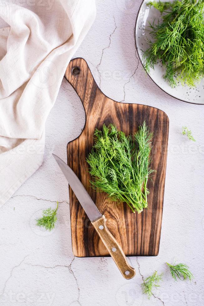 un montón de eneldo en una tabla de cortar sobre la mesa. condimento natural orgánico. vista superior y vertical foto