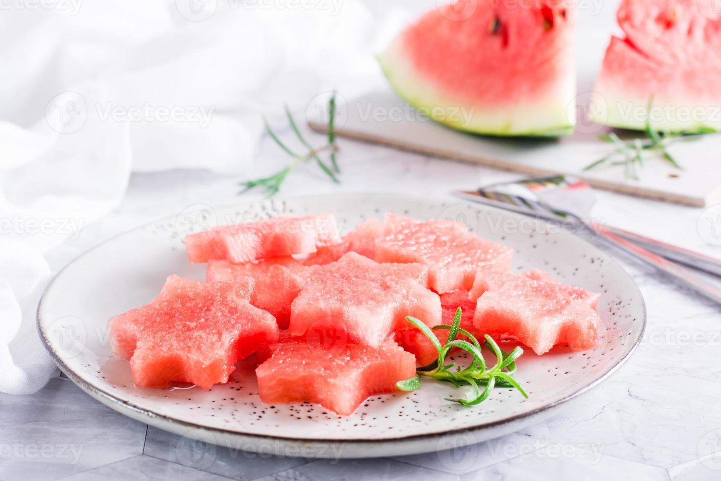 Pieces of fresh watermelon in the form of stars on a plate on the table. Summer refreshment. photo