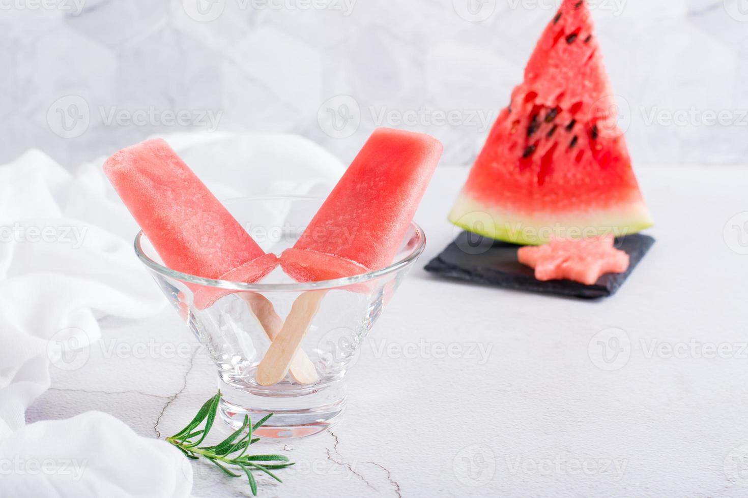 Watermelon popsicles in a bowl and a piece of watermelon on the table. Homemade dessert photo