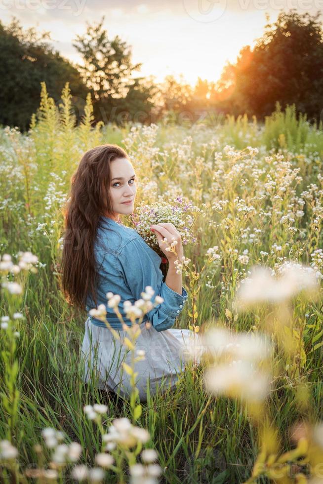 hermosa chica caminando en el campo en verano con flores silvestres. foto