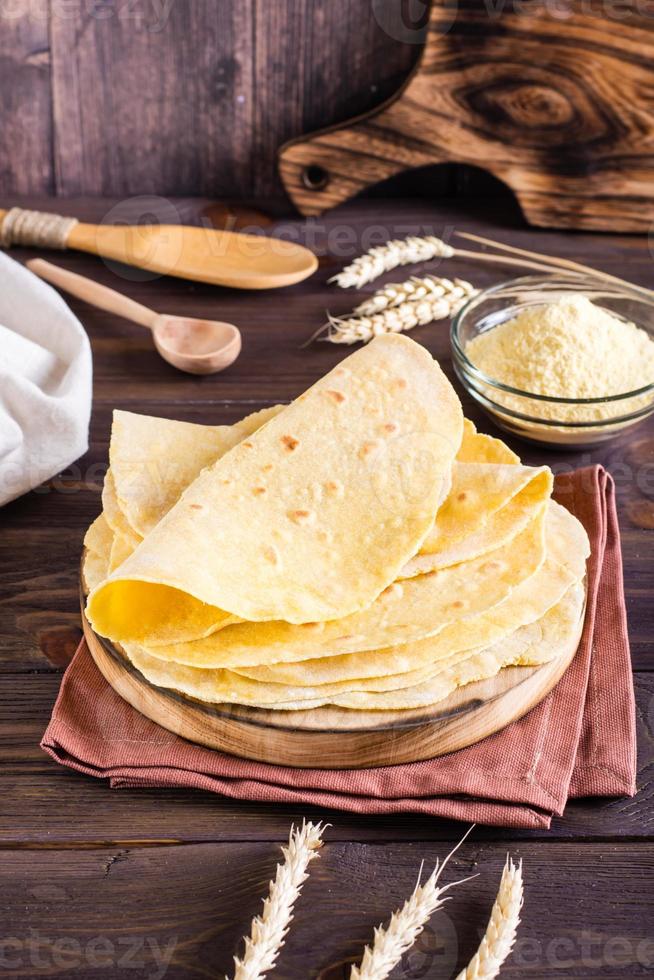 Homemade corn mexican tortillas wrap on a board on the table. Vertical view photo