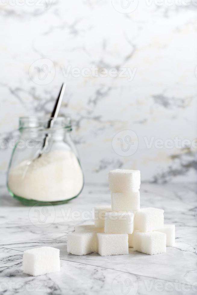 cubos de azúcar y azúcar granulada en un frasco sobre la mesa. vista vertical foto