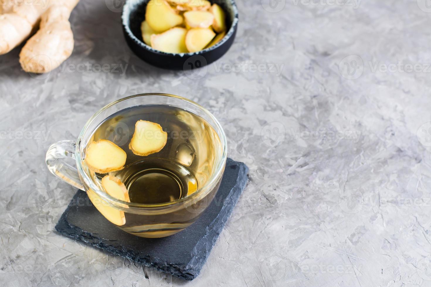 Fresh ginger tea in a cup and chopped ginger in a bowl on the table. Natural Vitamins. photo