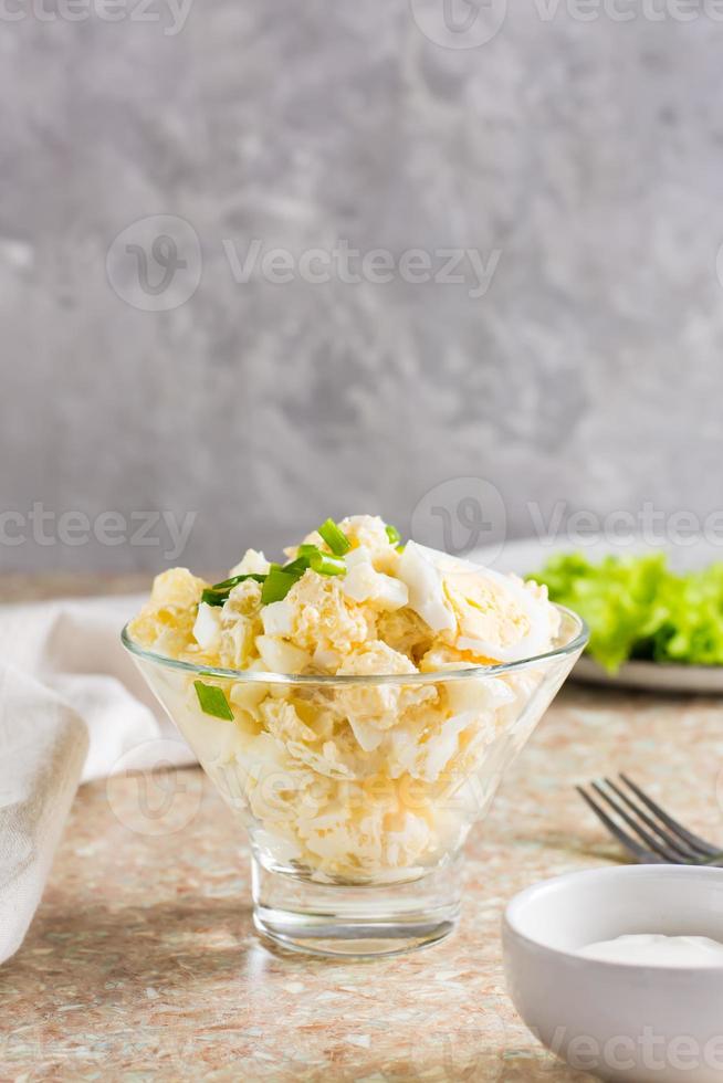 Homemade potato salad with egg and green onions in a bowl on the table